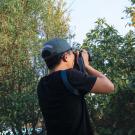 Person wearing an Arboretum and Public Garden cap photographing a fruit tree