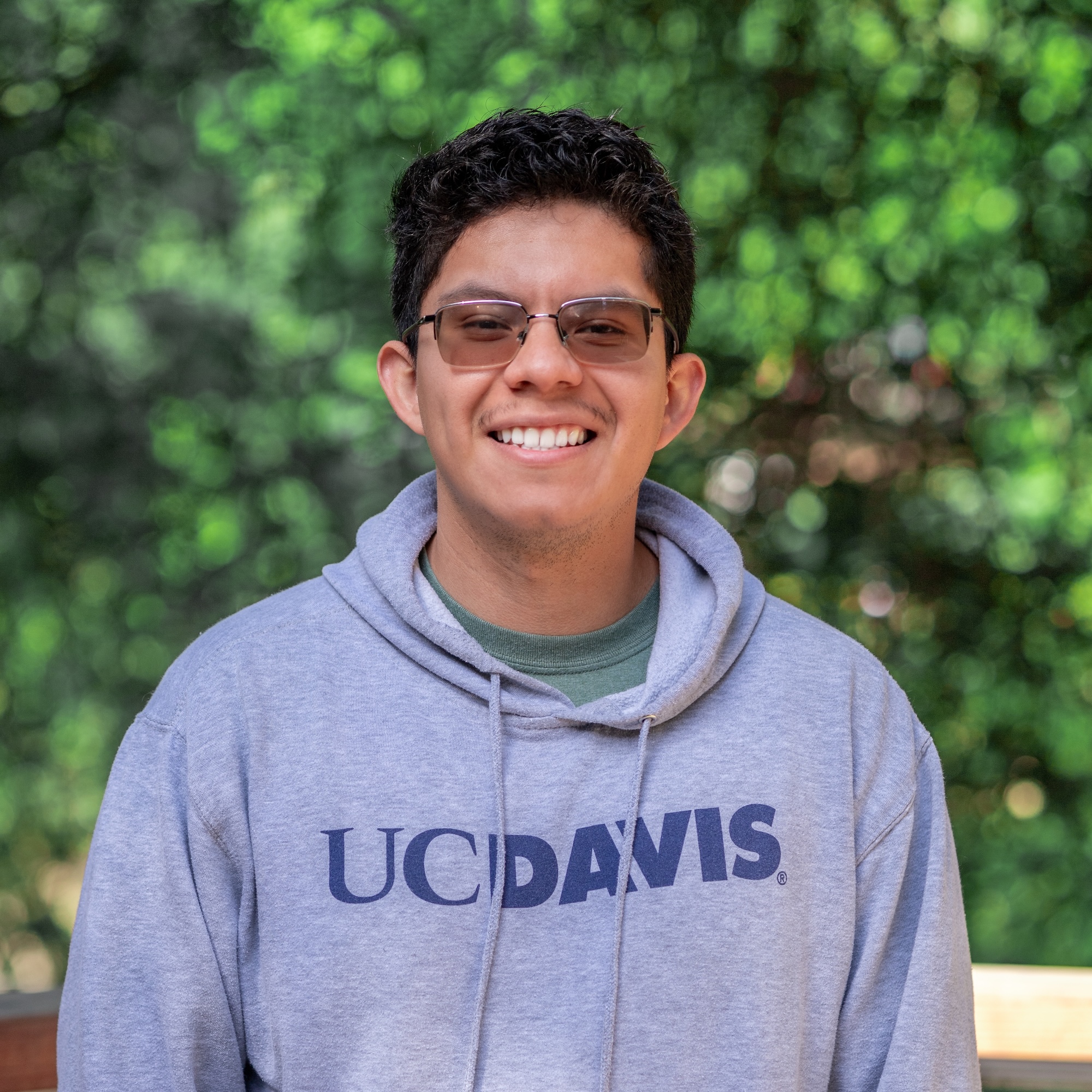 Marvin smiles, wearing a UC Davis hoodie, with leaves in the background