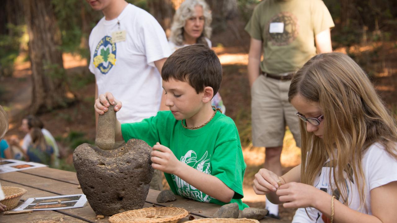 Image of child creating acorn flour from acorns.