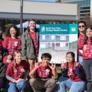 Group of Learning by Leading interns posing and smiling outdoors with a poster board with information on Climate Ready Gardening