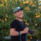 Matthew poses, smiling and holding a camera
